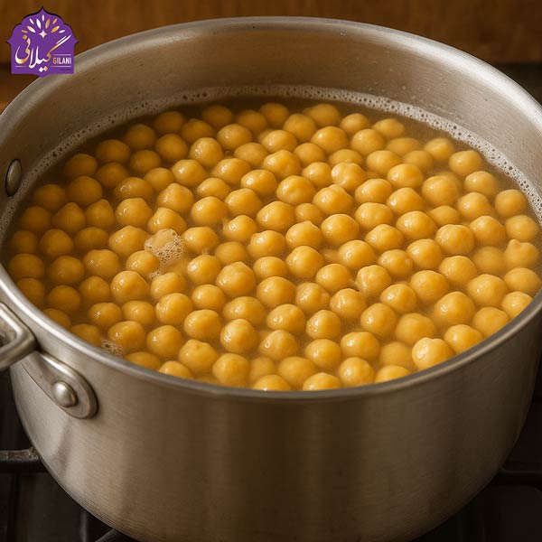 قابلمه استیل پر از نخود در حال جوشیدن در آب تازه روی اجاق برای تهیه حمص اصیل عربی